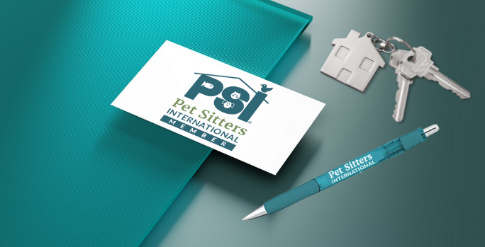 Pet Sitters International member business card is on table with a teal folder, house keys and pen